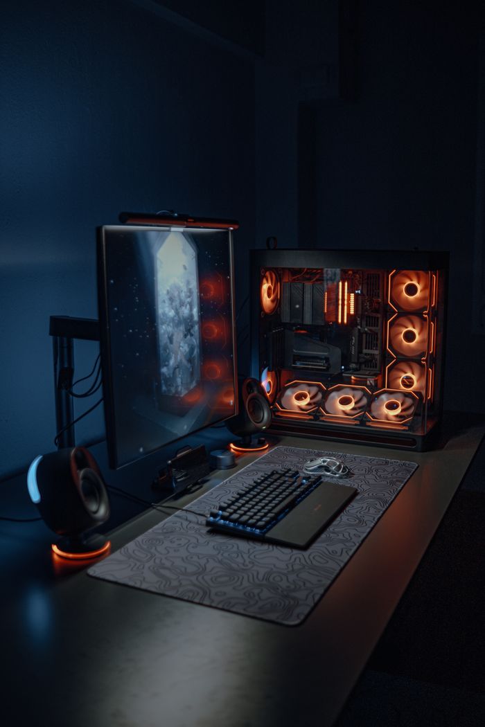 Contact Sleek gaming workstation with RGB-lit PC and peripherals in a dimly lit room.